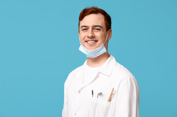 Male dentist with toothbrush and dental tools in pocket on blue background. World Dentist Day