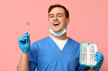 Male dentist with set of dental tools on pink background. World Dentist Day