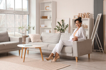 Young African-American businesswoman sitting on sofa at home
