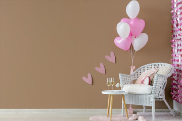 Armchair with heart-shaped balloons and pink hearts garland near brown wall. Valentine's Day...