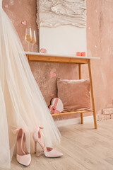 High-heels, wedding dress and heart-shaped gift box in festive room. Valentine's Day celebration