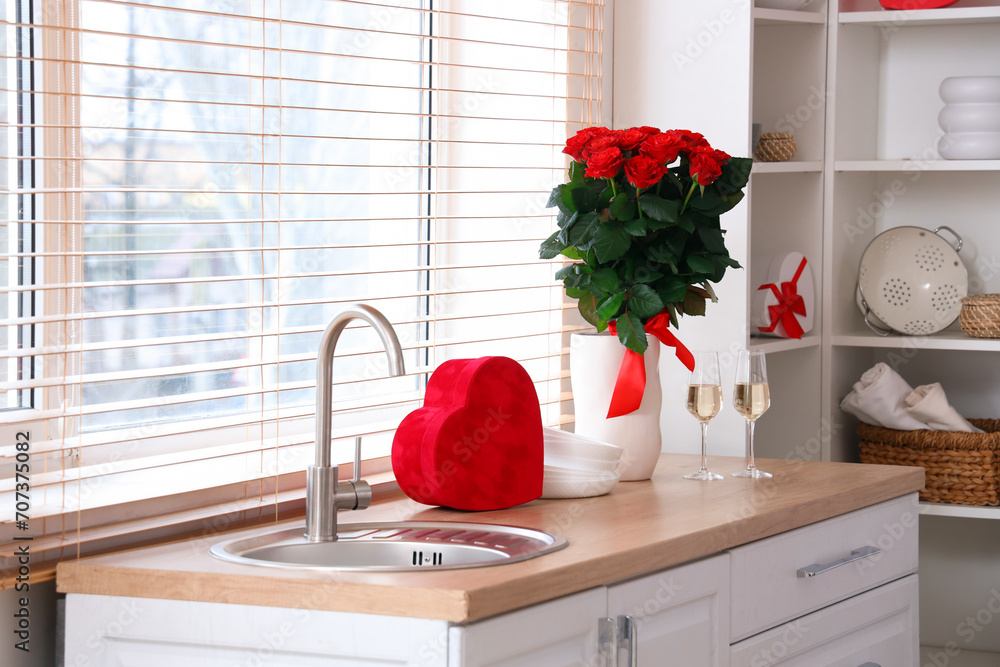 Sticker Vase with beautiful roses and heart-shaped gift box on kitchen counter. Valentine's Day celebrations