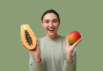 Beautiful young woman with sweet papaya and mango on green background