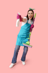 Pretty young woman with mop and bottle of detergent on pink background