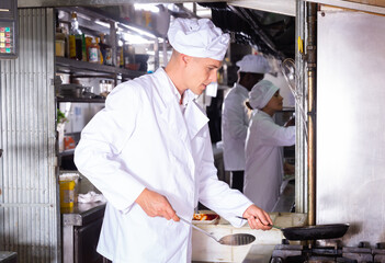 Fototapeta na wymiar portrait of smiling male chef grilling in modern kitchen