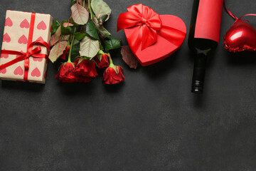 Bottle of wine with gift boxes, heart shaped air balloon and red roses on black background....