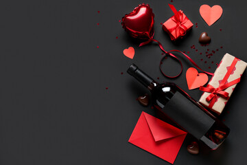 Bottle of wine with gift boxes, envelope, paper hearts, air balloon and chocolate candies on black...