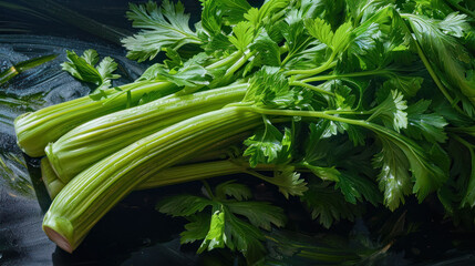  a pile of celery sitting on top of a black table next to a pile of green leafy vegetables on top of a black counter top of a table. - obrazy, fototapety, plakaty