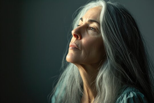 A captivating portrait of a wise and elegant woman with long, grey hair, her dark head covering framing her face as her piercing eyes and delicate lips speak volumes of her life's story