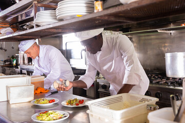 portrait of two happy man cooking dishes in restaurante