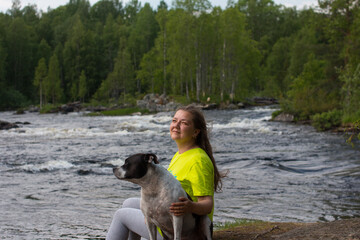 A woman on a walk with a dog against the background of a river threshold. Republic of Karelia wild...