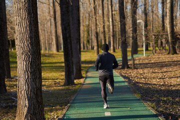 Athlete running in the park, view from back