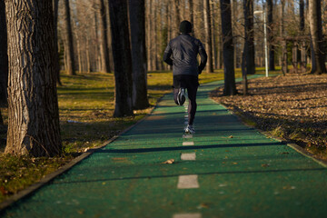 Athlete running in the park, view from back