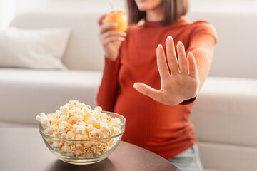 Unrecognizable Pregnant Woman Refusing Unhealthy Popcorn Choosing Apple Indoor, Cropped