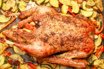 Close-up of a dish of baked duck stuffed with apples. The duck is baked with apples and served on a plate on a table.