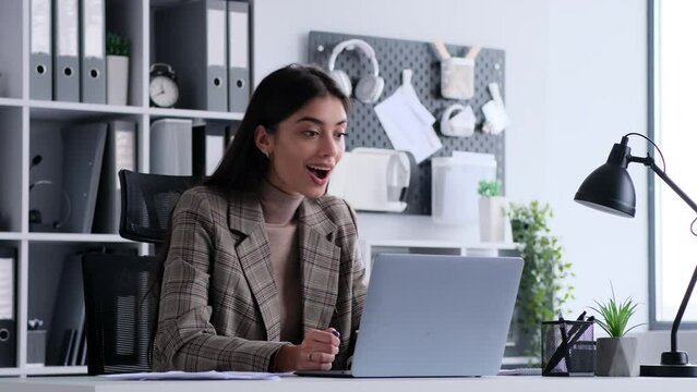 Celebrating a positive development, a businesswoman receives good news on laptop and expresses joy through applause. This image captures the elation and excitement associated with successful outcomes.