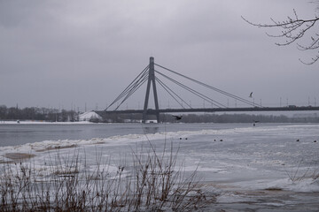 Kyiv, Ukraine - January 11, 2024. Outside, the temperature is sub-zero and frosty. A beautiful bridge can be seen behind. Light snow falls and sprinkles the city.
