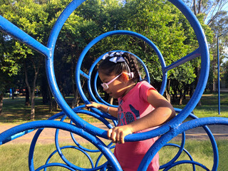 Obraz premium 4 year old Latina brunette girl plays in the park games under the sun without sun protection with risk of ultra violet rays