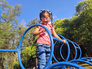 4 year old Latina brunette girl plays in the park games under the sun without sun protection with...
