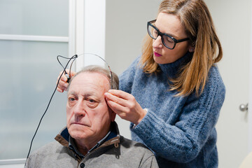 Audiologist putting bone headband to patient to check hearing loss