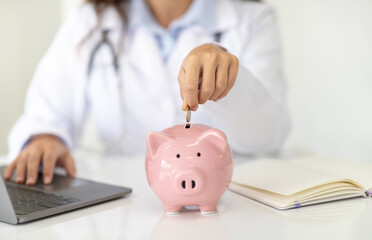 Cropped woman doctor general practitioner putting coin in piggy bank