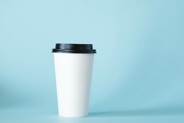 White coffee cup with black lid, blank, with a blue background.