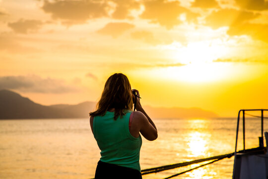 woman taking photos of the sea at sunrise