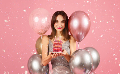 Joyous woman with a beaming smile celebrating with donuts topped with birthday candles