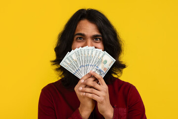 Excited millennial indian guy holding money cash in hand