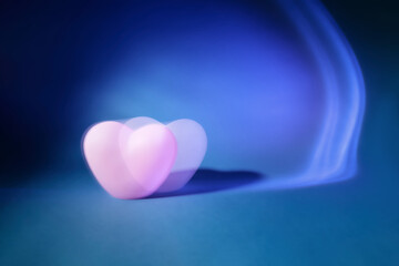 Abstract photography of two defocused pink heart making with long exposition on gradient light blue...