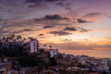 Dramatic Sunset over cityscape of Puerto Vallarta Jalisco Mexico in January with orange and purple hues.