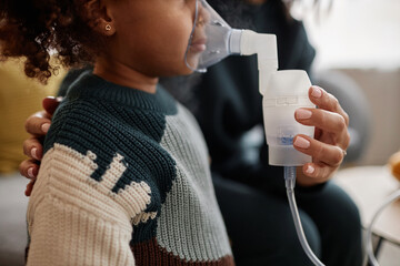 Cropped shot with side view of unrecognizable girl child in knitted sweater inhaling medicine steam from nebulizer mask - obrazy, fototapety, plakaty