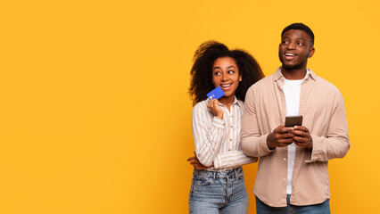 Happy black couple with credit card and smartphone, planning purchase, free space