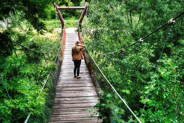 Blond kobieta na wiszącym moście w lesie. - obrazy, fototapety, plakaty