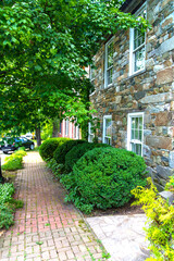 shady alley along the walls of ancient houses. The sidewalk is paved with stone.