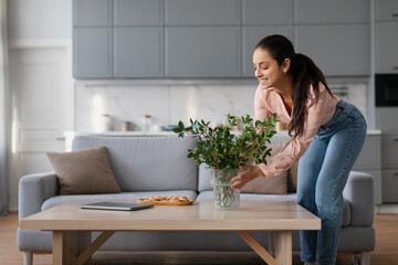 Woman arranging plant on table in living room