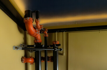 Exposed metal black and orange pipes curve around each other in a building ceiling.  