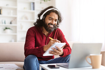 Joyful indian guy have online training at home, using laptop