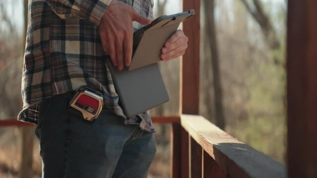 Young male contractor using Tablet while examining house exterior