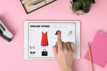 Woman with tablet shopping online on pink background, top view