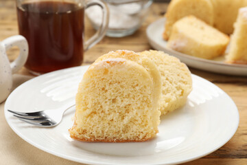 Pieces of delicious sponge cake and fork on wooden table, closeup