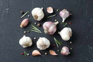 Fresh garlic, rosemary and peppercorns on dark textured table, flat lay