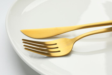 Clean plate, fork and knife on white background, closeup