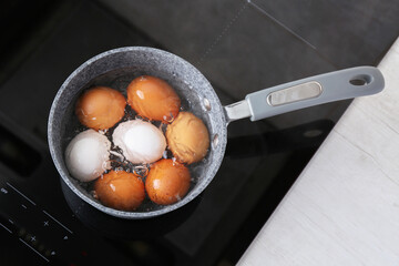 Chicken eggs boiling in saucepan on electric stove, top view