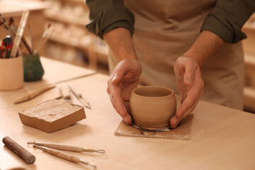 Fototapeta na wymiar Clay crafting. Man making bowl at table indoors, closeup