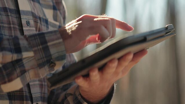 Young male contractor using Tablet while examining house exterior