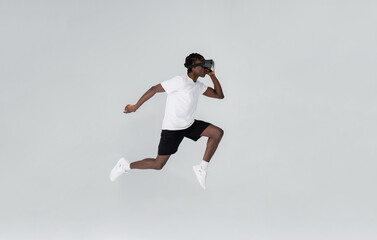 Fototapeta na wymiar In motion shot of black man wearing vr headset running in studio