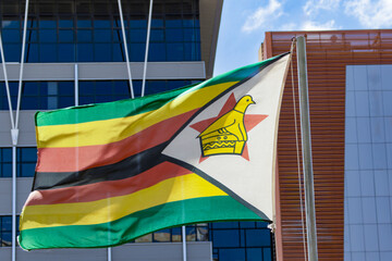zimbabwe flag on the pole, blue sky with clouds