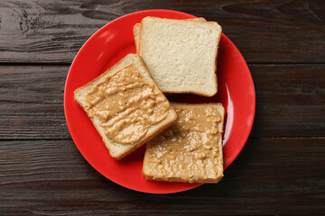 Delicious toasts with peanut butter on dark wooden table, top view