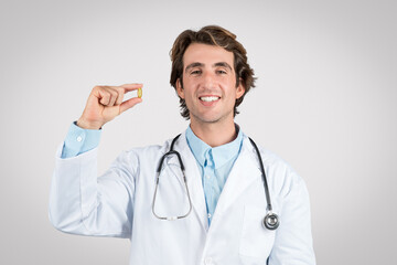 Happy male doctor showing a supplement pill